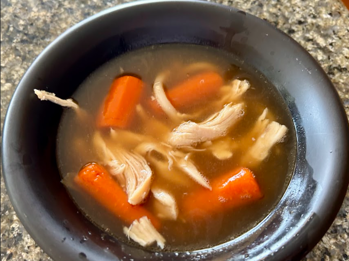Chicken soup in black bowl.