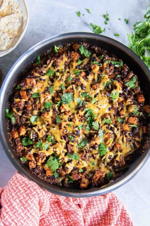 Mexican quinoa with sweet potatoes, cheese and cilantro in a skillet.