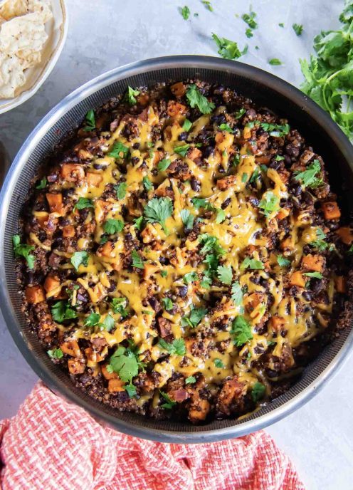 Mexican quinoa with sweet potatoes, cheese and cilantro in a skillet.