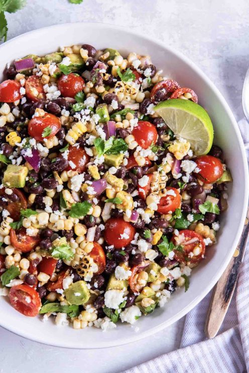 Corn salad in a serving bowl with a lime wedge.