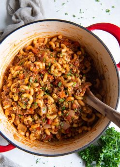 Goulash in a Dutch oven pot with a wooden spoon.