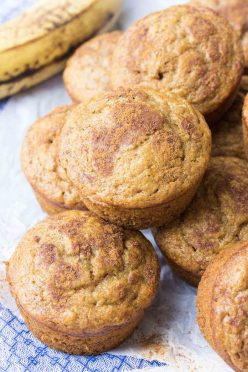 Muffins stacked together with ripe banana in the background.