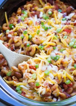 Vegetarian chili mac topped with cheese and green onions in a slow cooker.