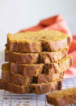 Five slices of pumpkin bread stacked on a wire rack.