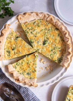 Partially sliced broccoli quiche in pie dish.