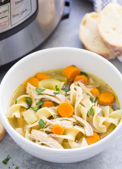 Instant Pot Chicken Noodle Soup in a white bowl with a pressure cooker in the background.