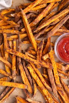 Baked sweet potato fries served with small dish of ketchup.