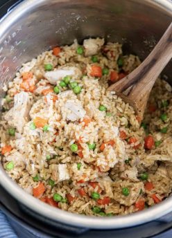 Chicken and rice in Instant Pot with wooden spoon.