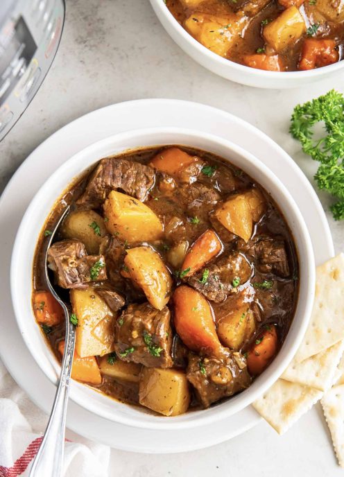 Instant pot beef stew in a bowl with a spoon.