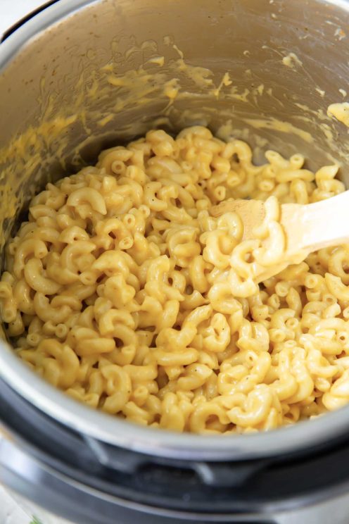 Creamy mac and cheese in Instant Pot with wooden spoon.