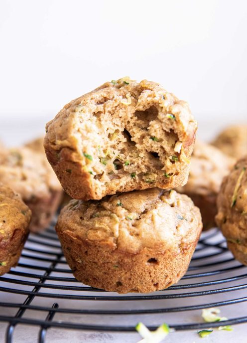 Stack of two zucchini muffins with a bite taken out of the top muffin.