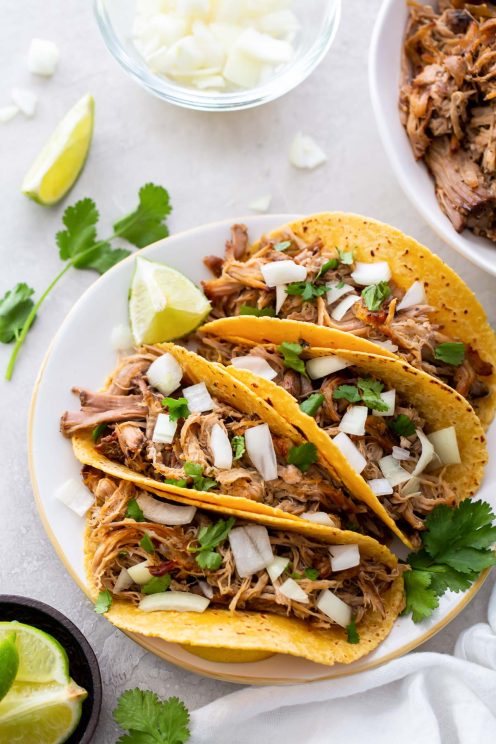 Four pork carnitas tacos on a plate.