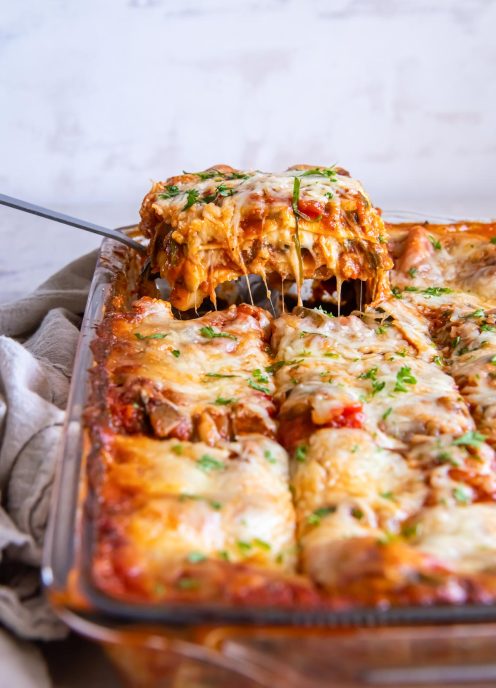 Slice of vegetable lasagna being removed from casserole dish.
