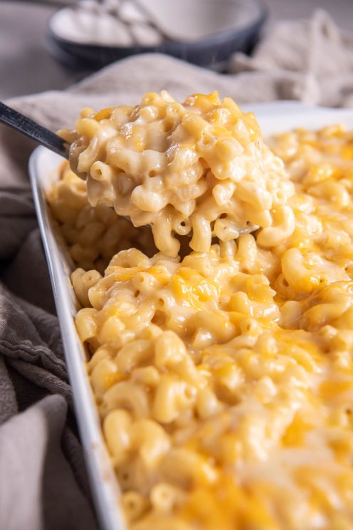 Macaroni and cheese on a serving spoon held over baking dish.