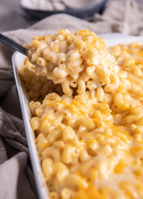 Macaroni and cheese on a serving spoon held over baking dish.