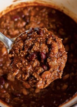 Ladle full of chili held over pot of chili.