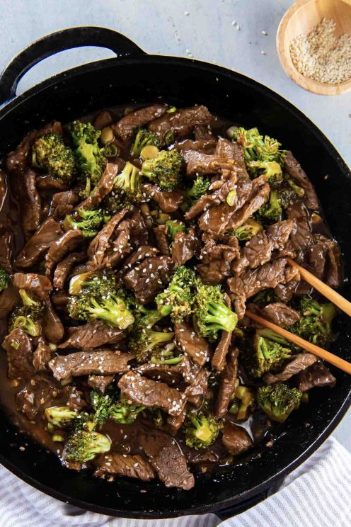 Beef and broccoli in a cast iron skillet with chopsticks.