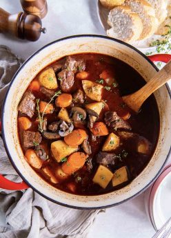 Beef stew in a pot with a wooden spoon.