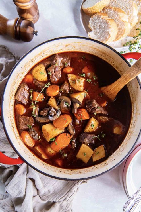 Beef stew in a pot with a wooden spoon.