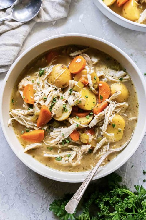 Bowl of slow cooker chicken stew with a spoon resting in it.