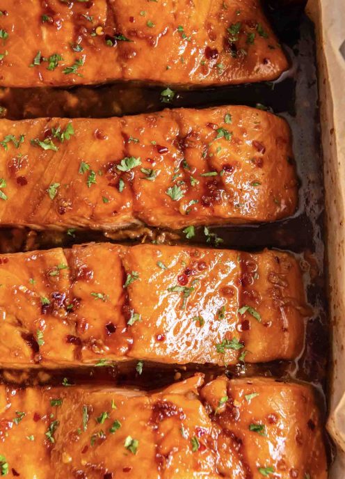 Four honey glazed baked salmon fillets in baking dish.