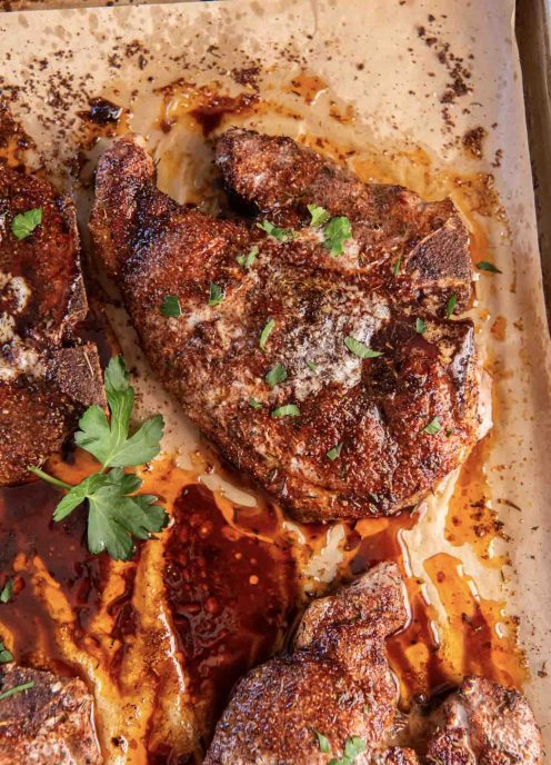 Baked bone-in pork chops on a parchment paper lined baking sheet.