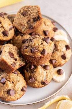 Banana chocolate chip muffins stacked on a plate.