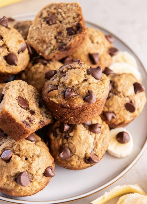 Banana chocolate chip muffins stacked on a plate.