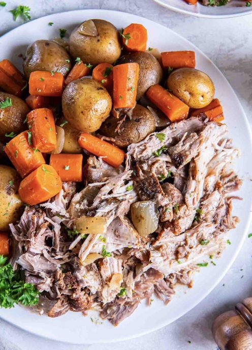 Shredded pork roast with potatoes and carrots on a serving plate.