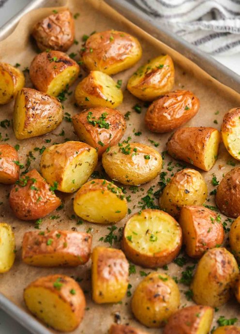 Roasted potatoes on baking sheet garnished with chopped fresh parsley.