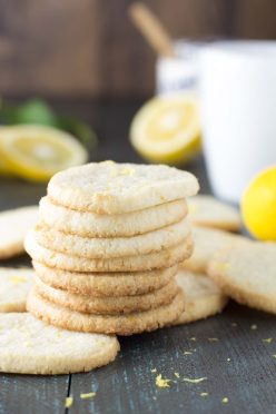 Stack of 7 lemon almond shortbread cookies with fresh lemons in the background.